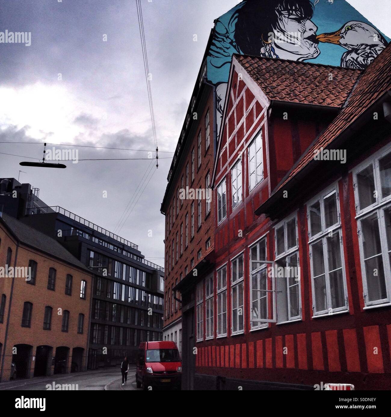 Wandern in einem bewölkten Tag in einer skandinavischen Stadt unter ein Gemälde eines Kusses zwischen einer Frau und eine Möwe - Smartphone-aufgenommenes Stockfoto