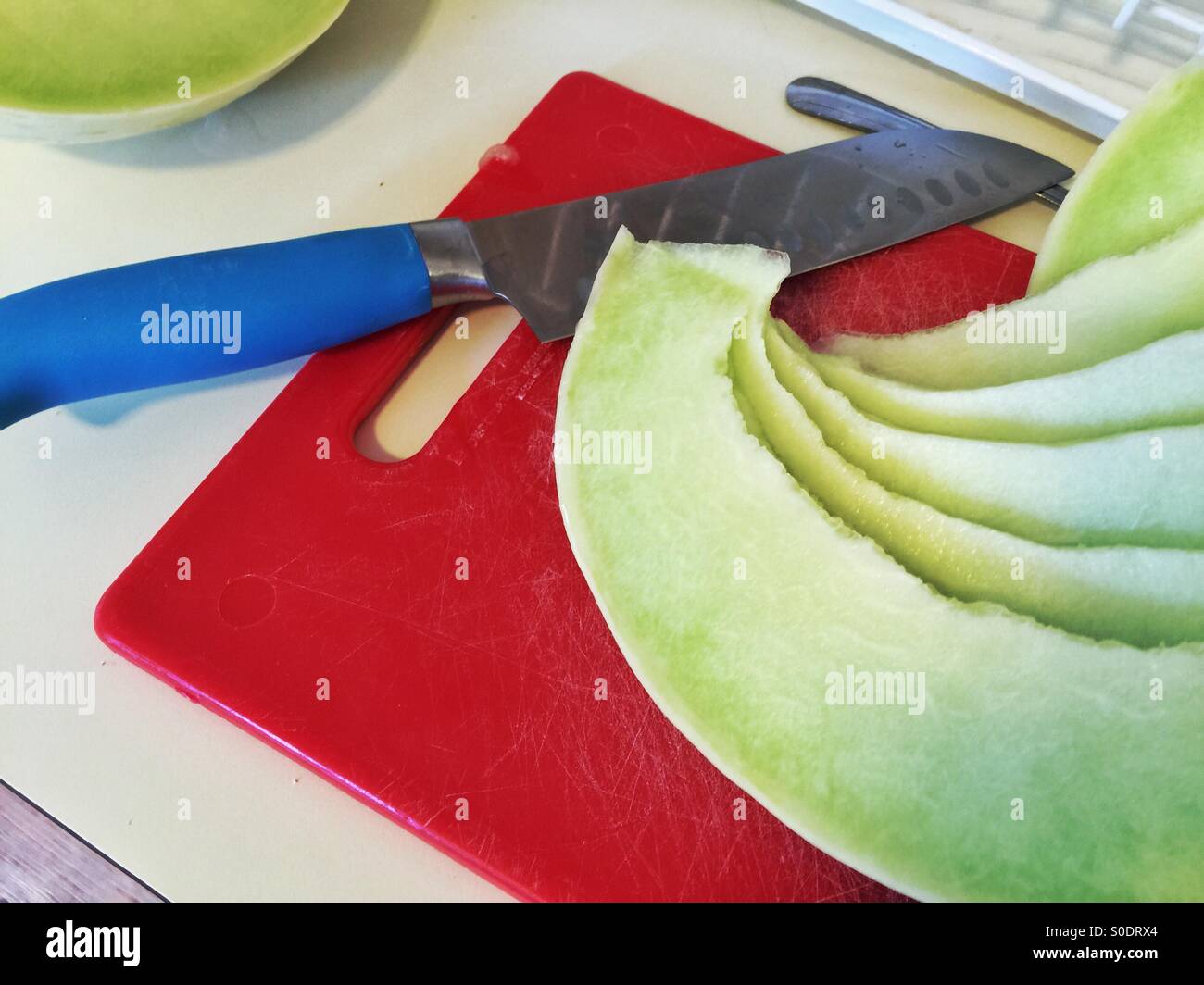 Honigmelone-Scheiben auf Schneidebrett rot - Smartphone-aufgenommenes Stockfoto