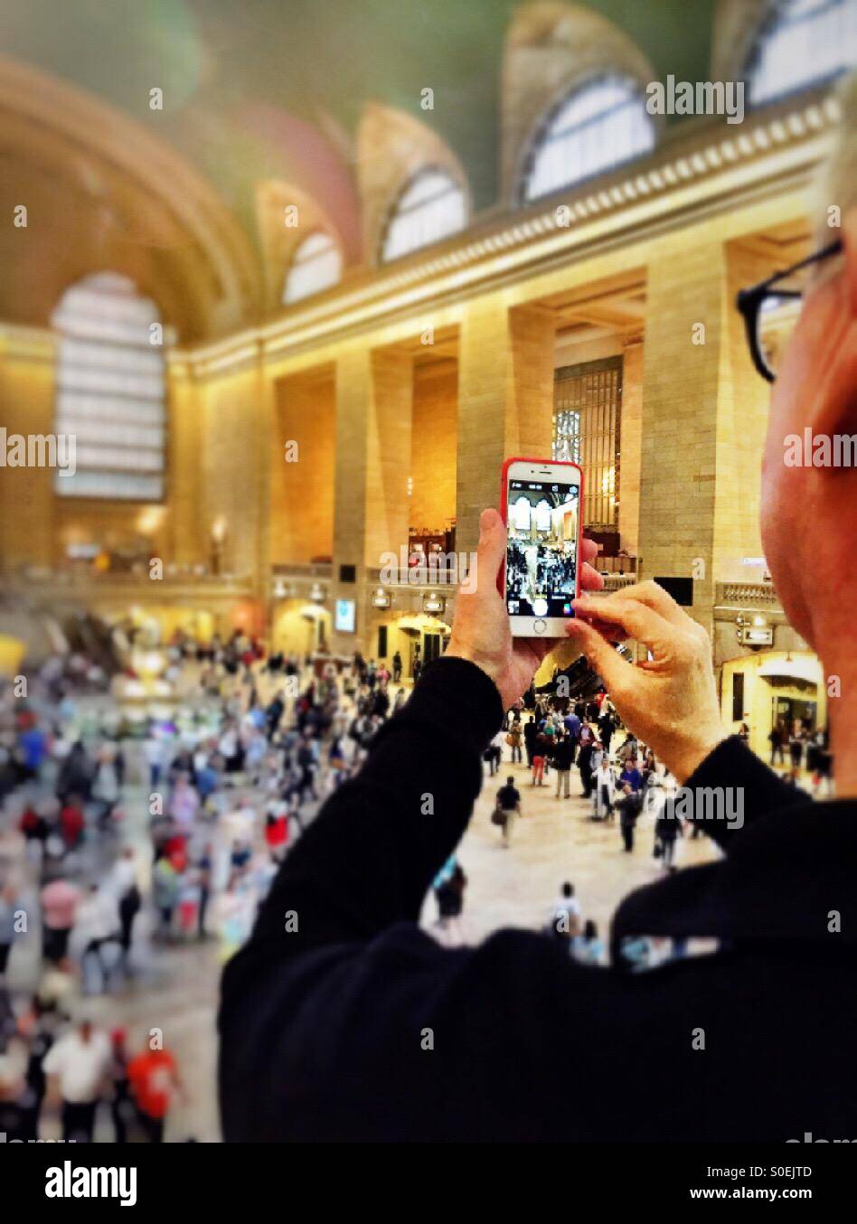 Reifer Mann Handy-Aufnahme im Bahnhof grand central Station. NEW YORK CITY - Smartphone-aufgenommenes Stockfoto