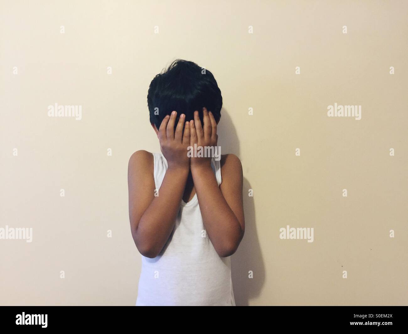 Junge versteckt Gesicht mit Händen Stockfoto
