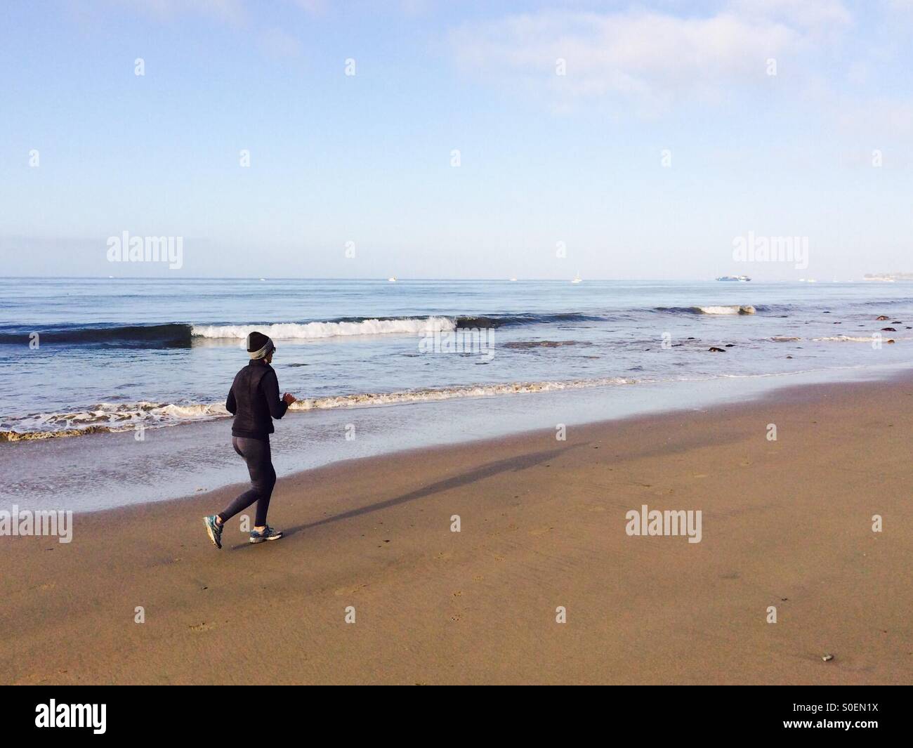 Joggen Sie am frühen Morgen am Strand entlang Stockfoto