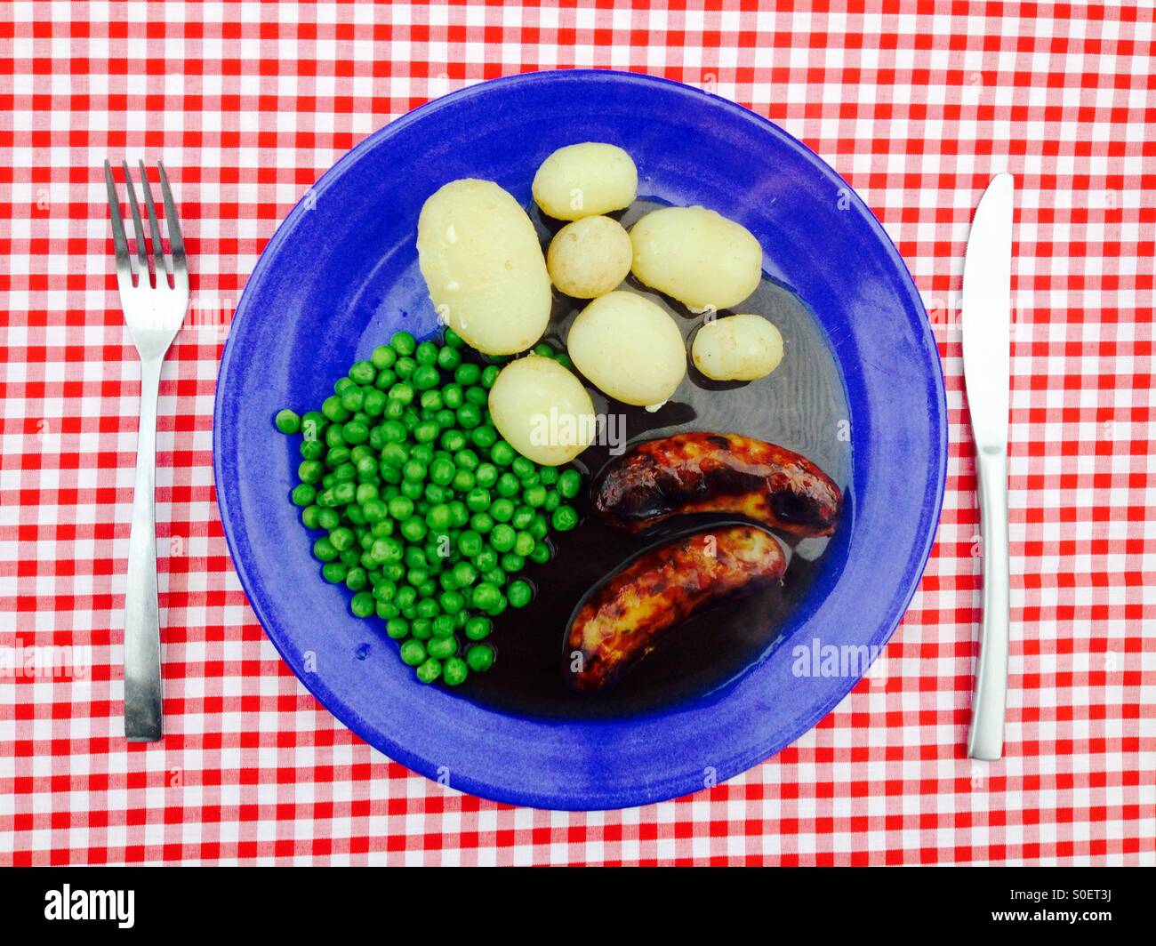 Neue Kartoffeln, Würstchen aus Schweinefleisch, Erbsen und Soße. - Smartphone-aufgenommenes Stockfoto