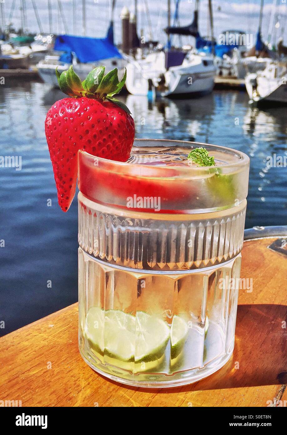 Ein Obst- und Kräutergarten infundiert Glas Wasser ruht auf dem Achterdeck Schiene eines Bootes für ein erfrischendes Getränk mit Blick auf andere Boote im Hintergrund. Stockfoto