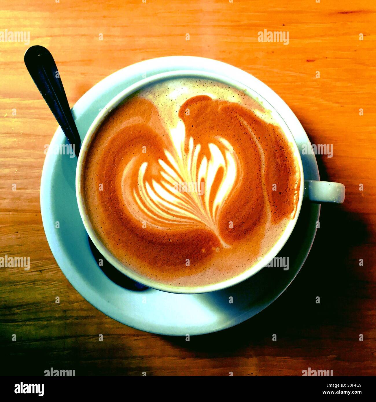 Barista gestaltete Kunstwerke in einer einzigen herzhaften heißen Tasse Kaffee aus biologischem Anbau. San Francisco, CA, USA. - Smartphone-aufgenommenes Stockfoto