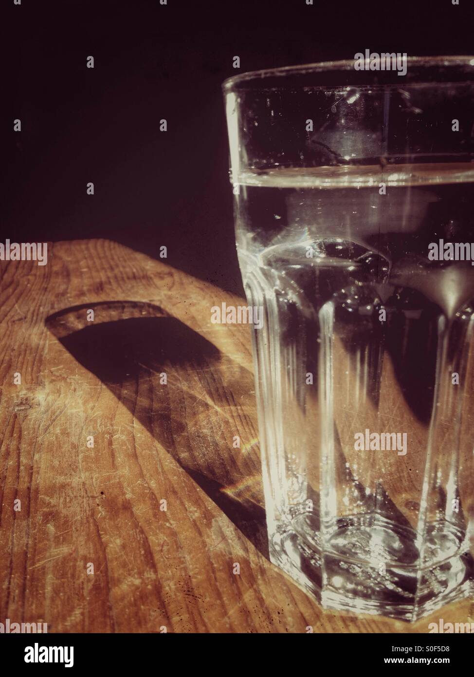 Reflexion von einem Glas Wasser auf einem Holztisch Stockfoto