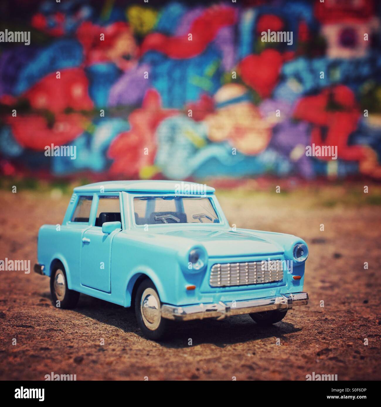 Berlin - ein Trabant Modellauto mit Graffiti hinter Stockfoto