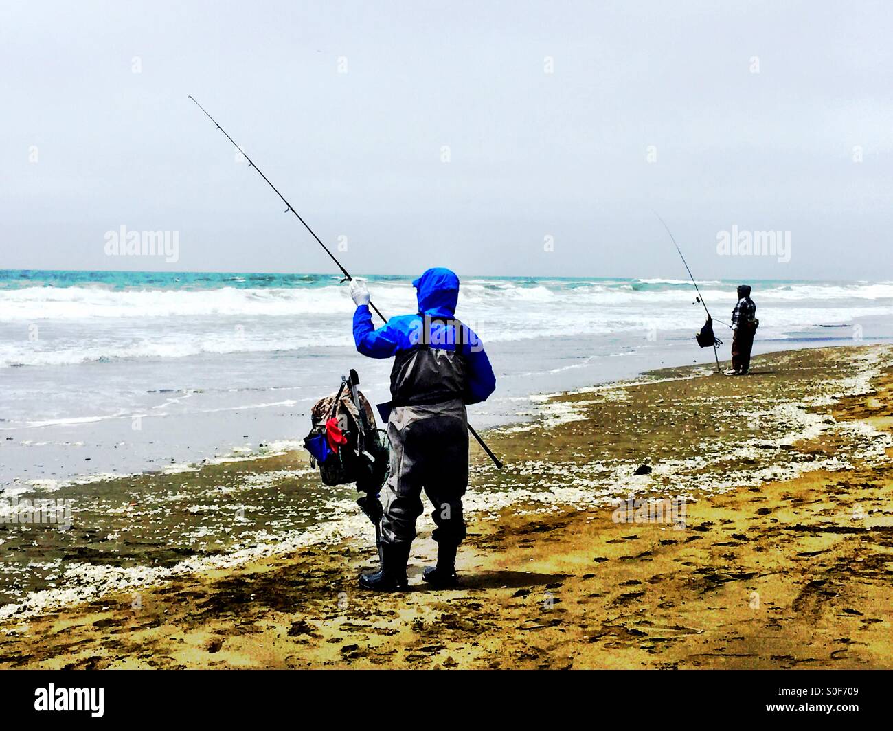 Zwei lokale Fischer arbeiten ihre Ruten und Rollen an einem langen, weiten von Northern California Beach. Stockfoto