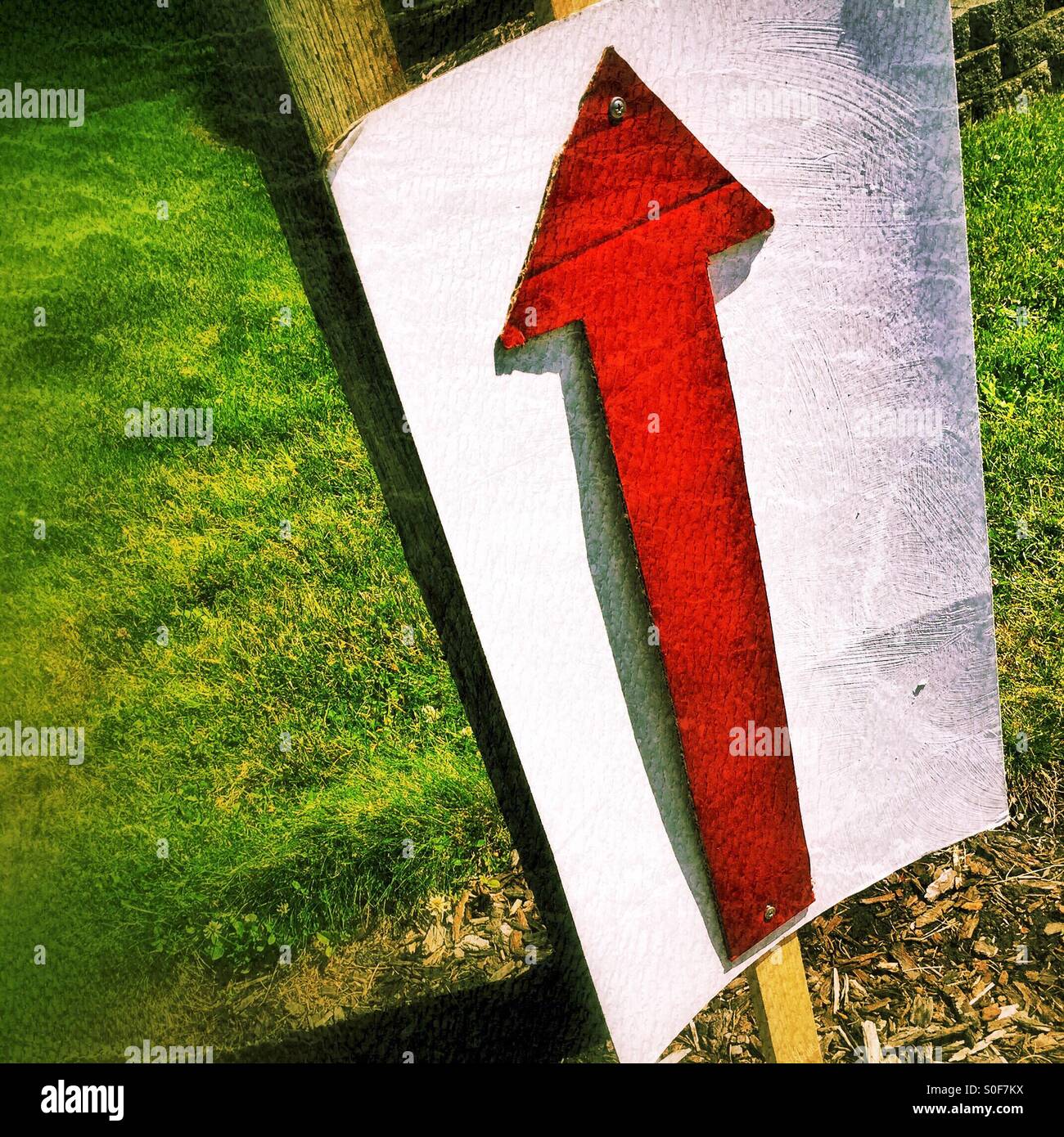 Ein roter Pfeil auf einem Schild am Straßenrand weist den Weg zu gehen. Stockfoto