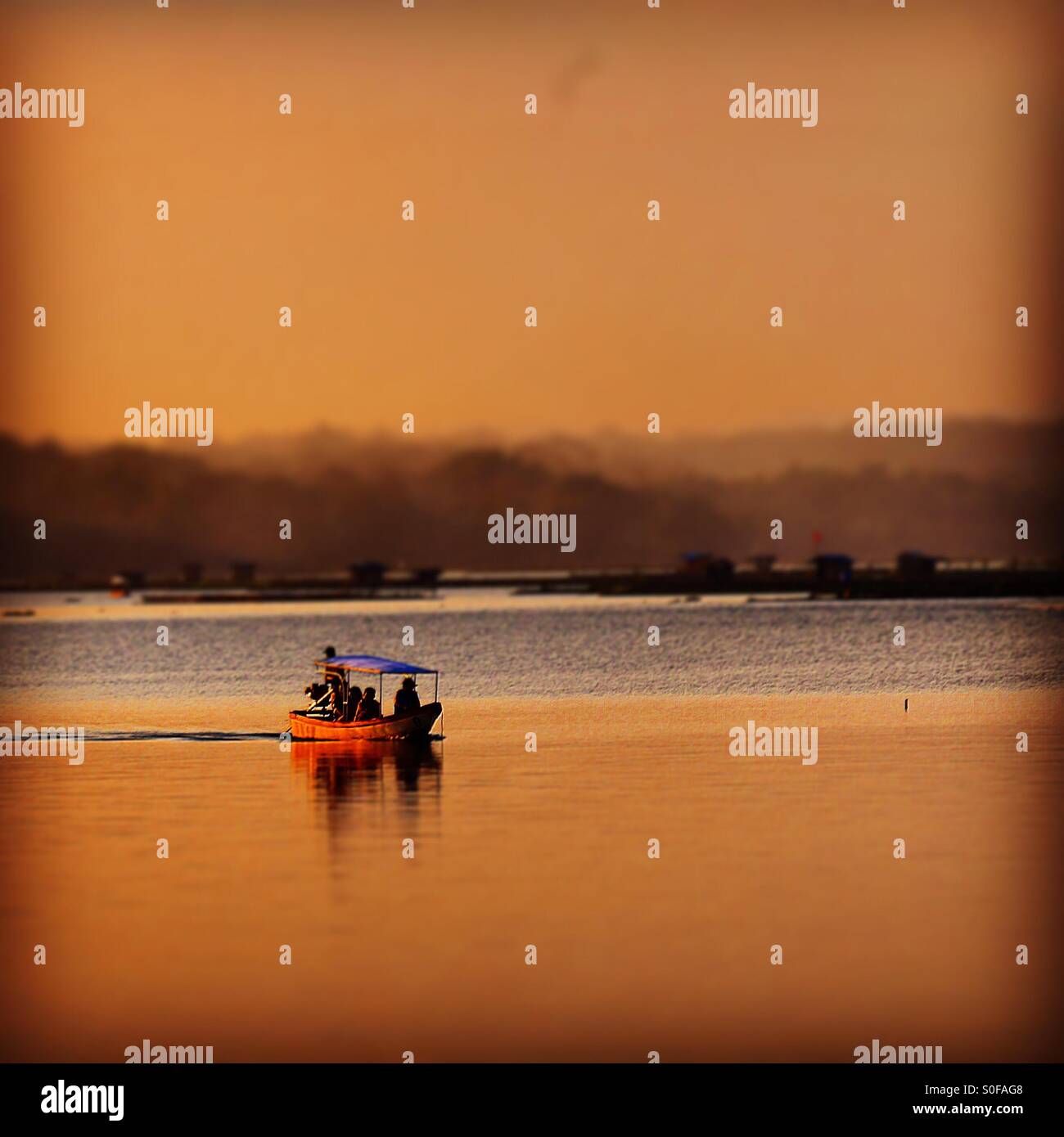 Ein Boot über den See (Sebuah Perahu Melewati Danau Membawa Penumpang) Stockfoto