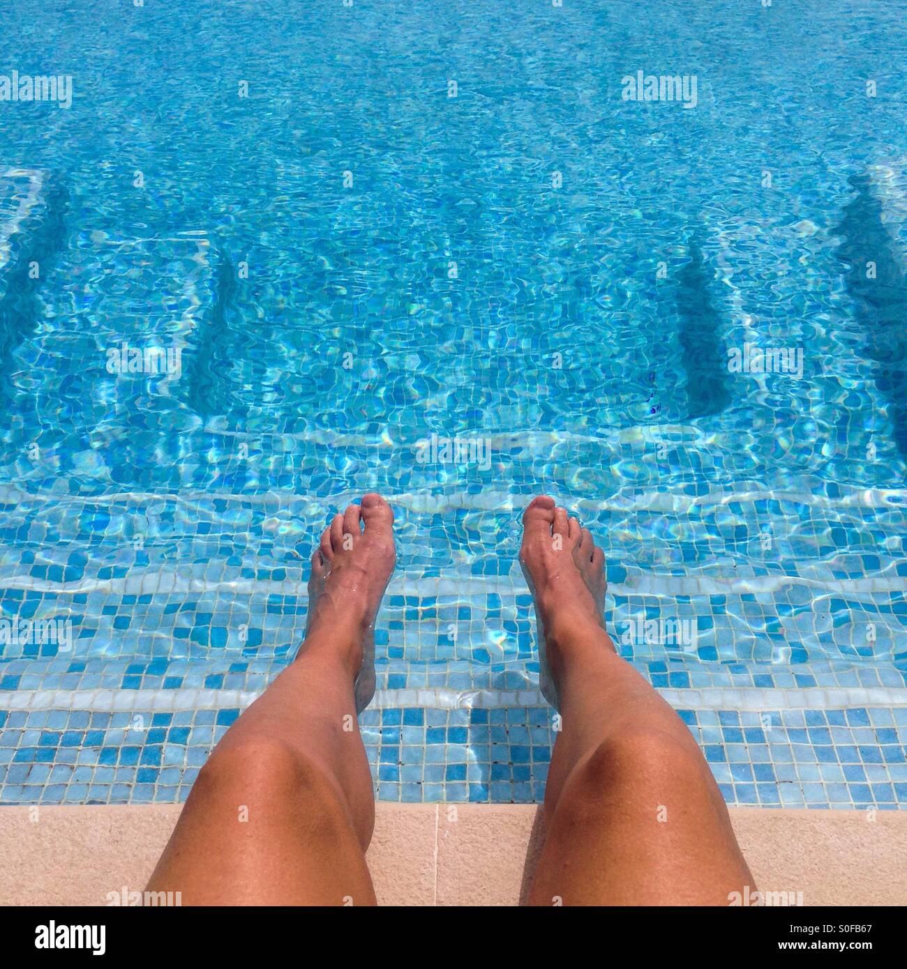 Füße und Beine auf einen Pool mit einer quadratischen Form von Schritten - Smartphone-aufgenommenes Stockfoto