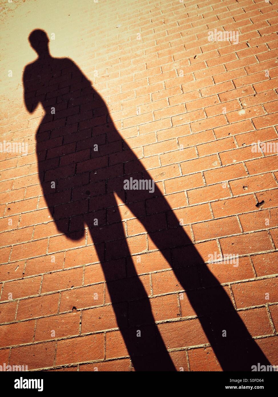 Schatten eines Mannes mit einer schweren und großen Tasche Stockfoto