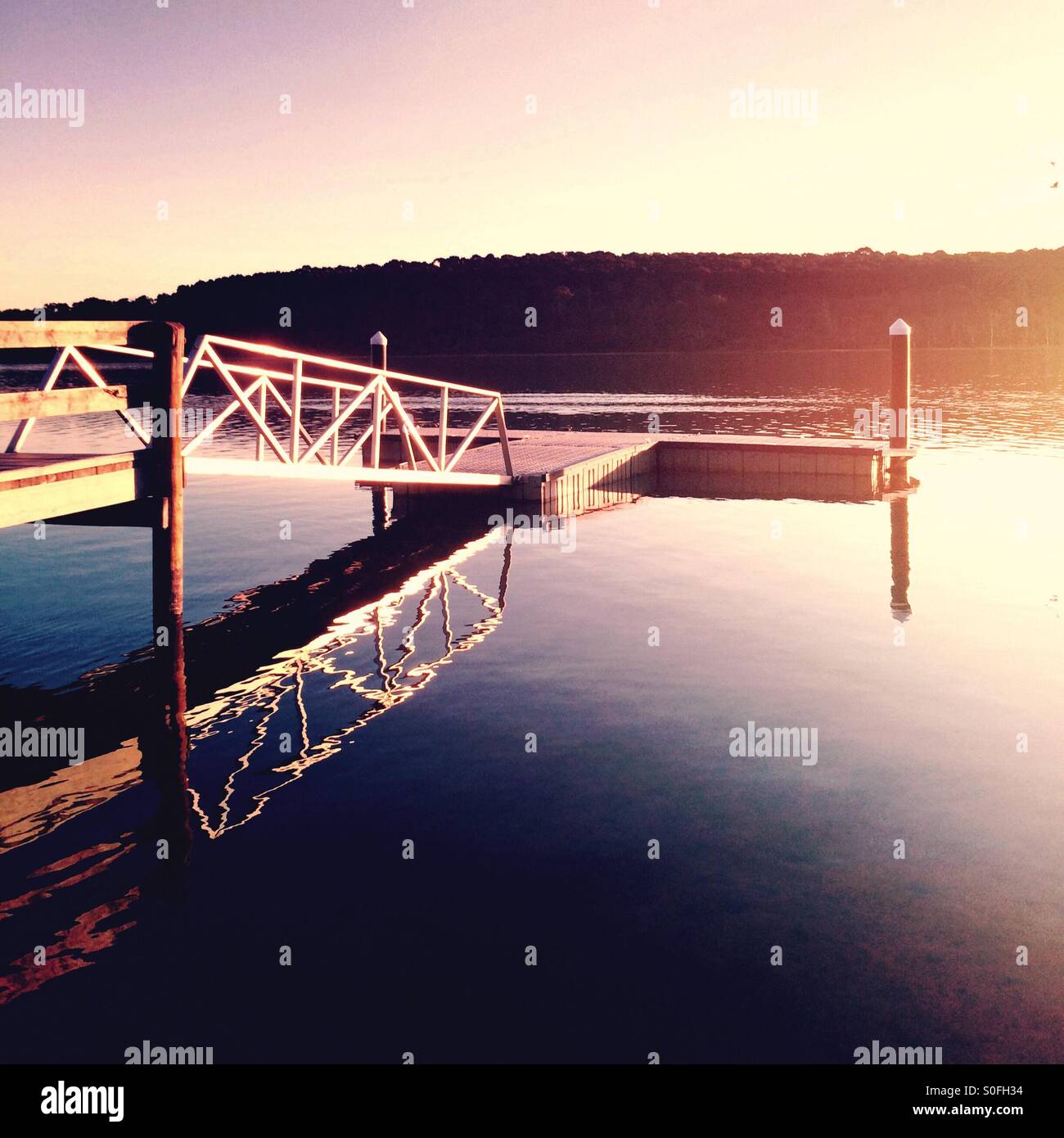 Ruhige See mit Steg und späten Nachmittagssonne Stockfoto