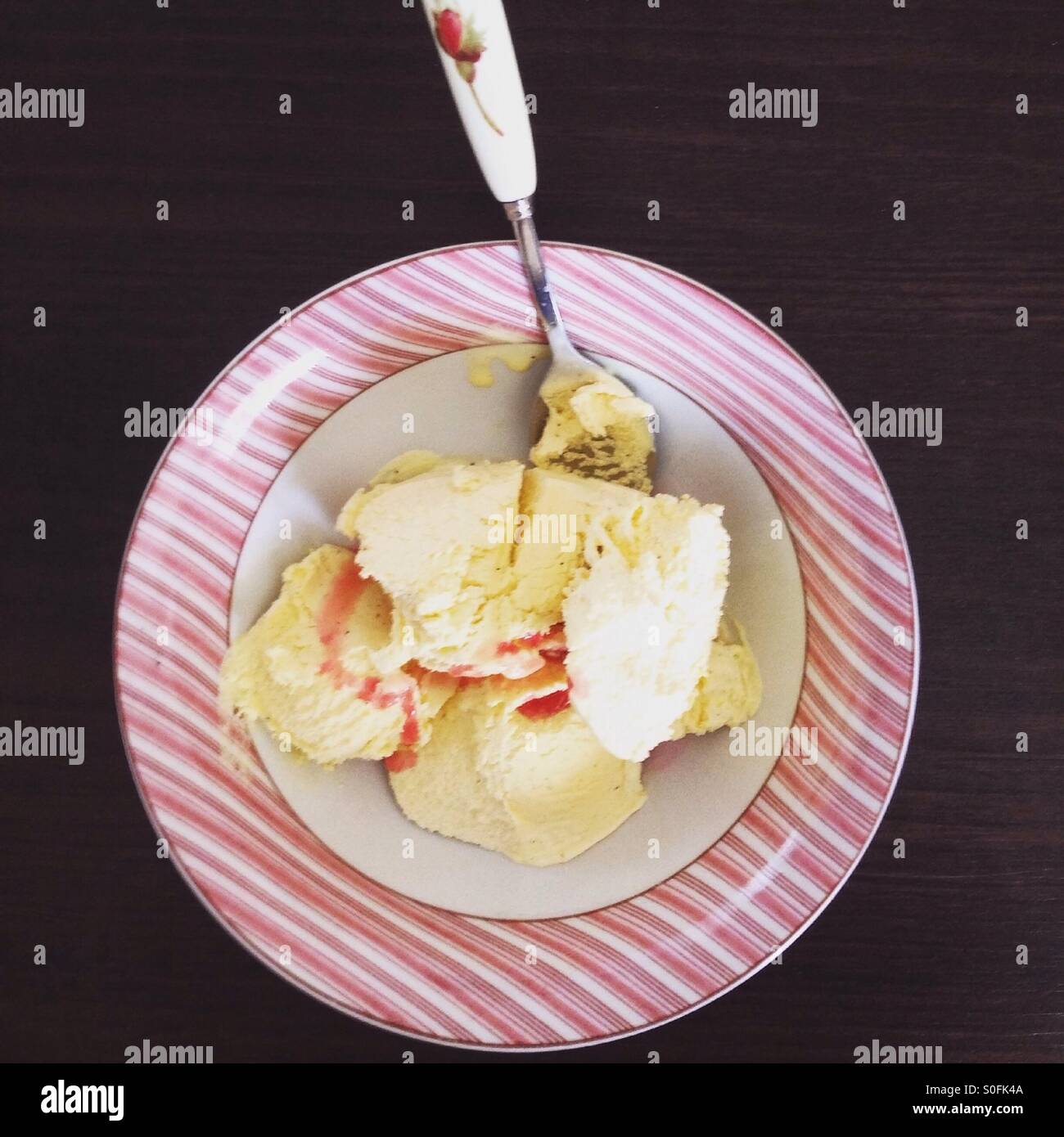 Vanilleeis mit Kirschsauce auf dunklem Holz Stockfoto