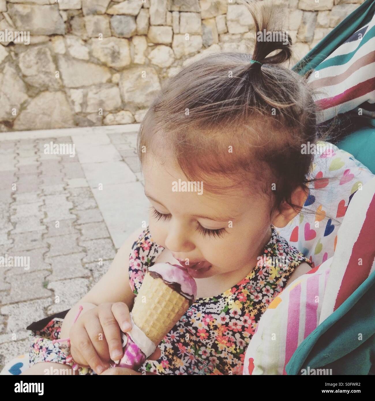 Babymädchen essen Eis im freien Stockfoto