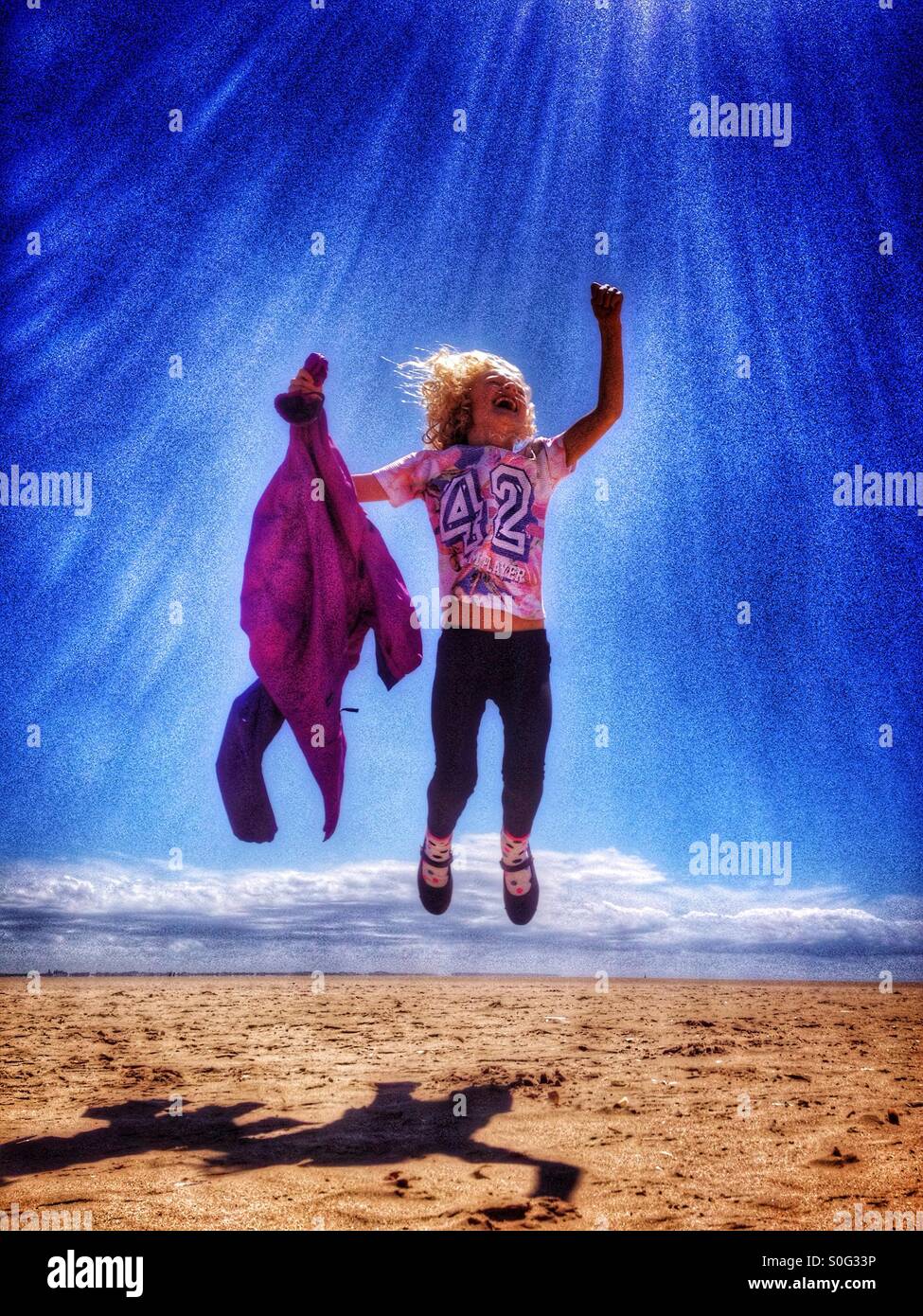 Junges Mädchen springen vor Freude am Strand in Lytham St Annes Stockfoto