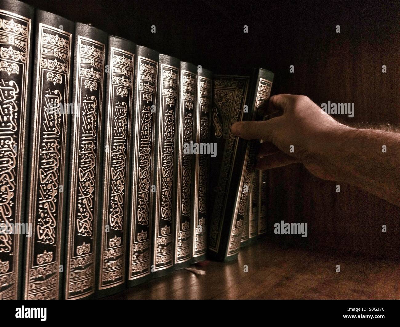 Den Heiligen Koran aus dem Regal Kommissionierung Mann - Smartphone-aufgenommenes Stockfoto