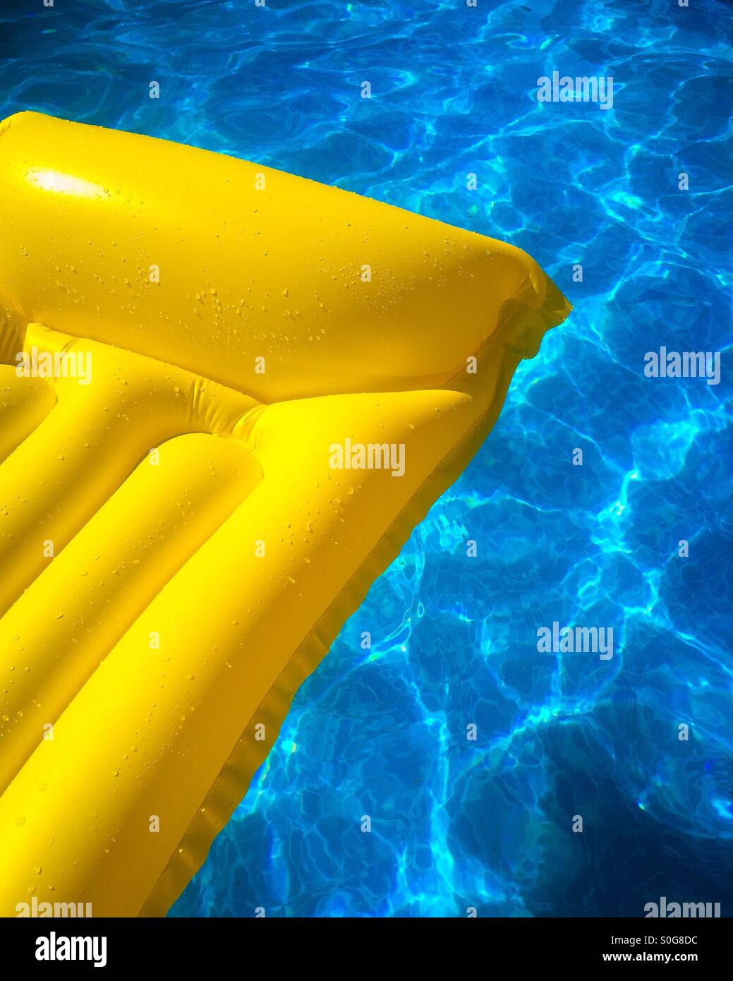 Gelbe aufblasbare Matte schweben im Schwimmbadwasser. Stockfoto