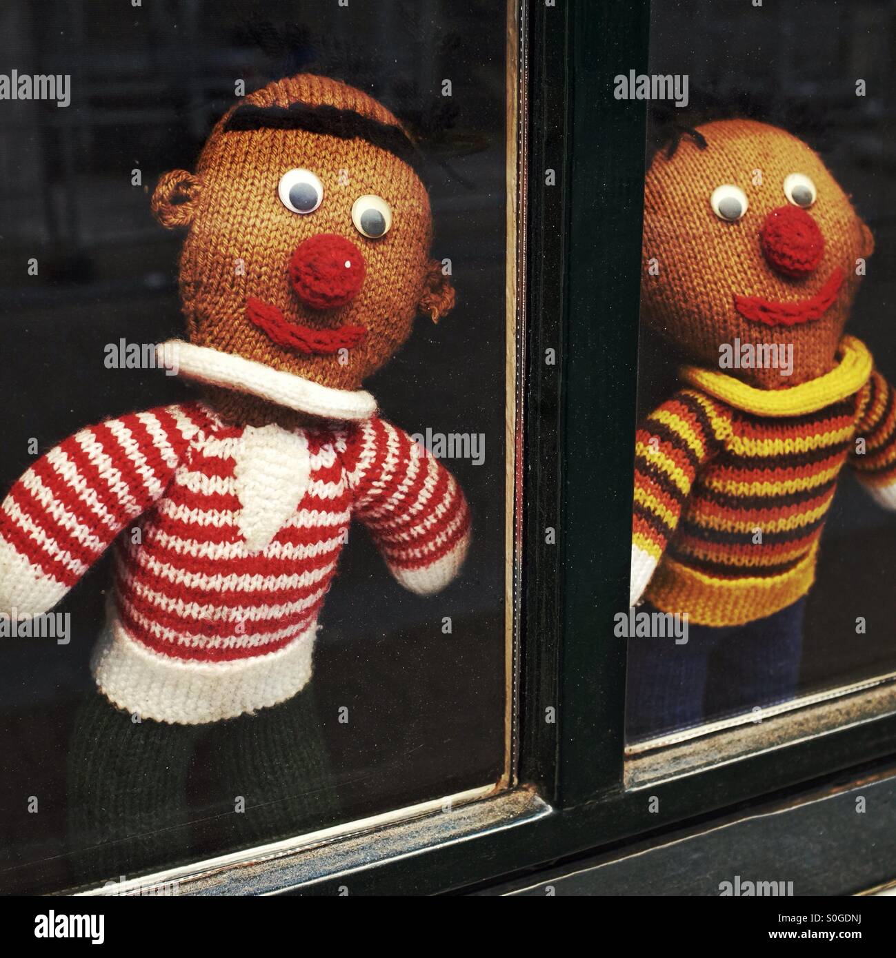 Nachbarschaft Uhr - zwei gestrickte Zeichen Ausschau aus einem Fenster Stockfoto