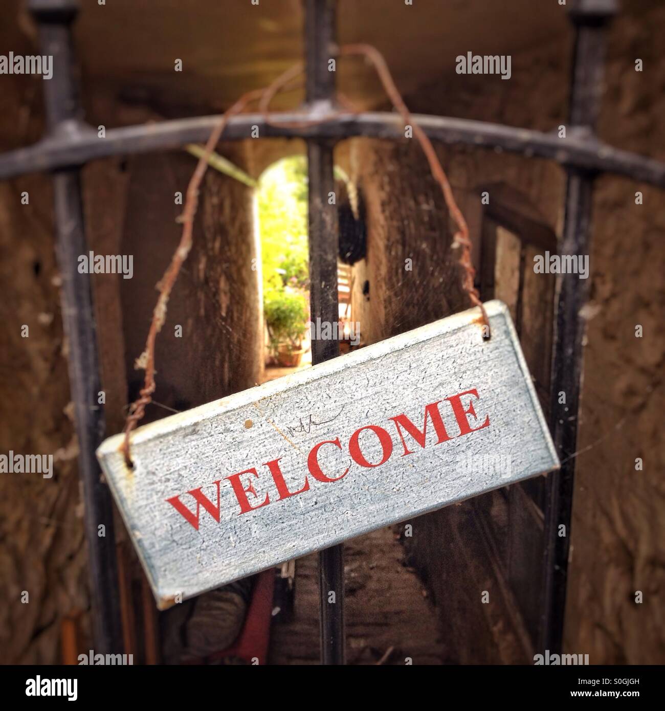Willkommensschild auf eingezäunten Gasse durch Haus. - Smartphone-aufgenommenes Stockfoto