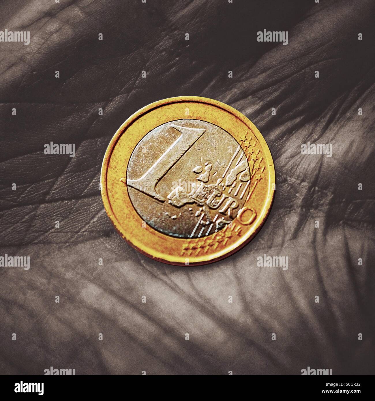 Eine Nahaufnahme von ein-Euro-Münze in der Hand eines Rentners Stockfoto