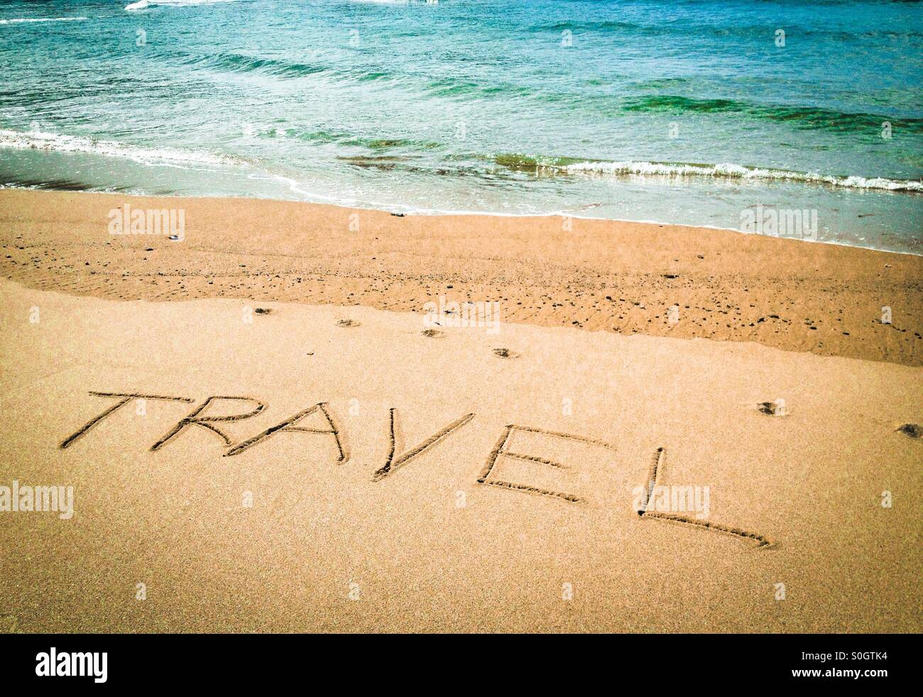 Das Wort Reisen in den Sand geschrieben - Smartphone-aufgenommenes Stockfoto