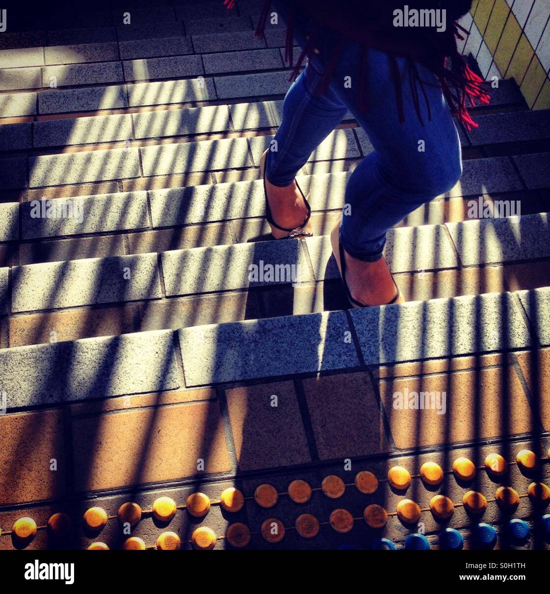 Die untere Hälfte einer Person zu Fuß, eine Treppe in der Diagonale Schatten am Morgen bedeckt Stockfoto