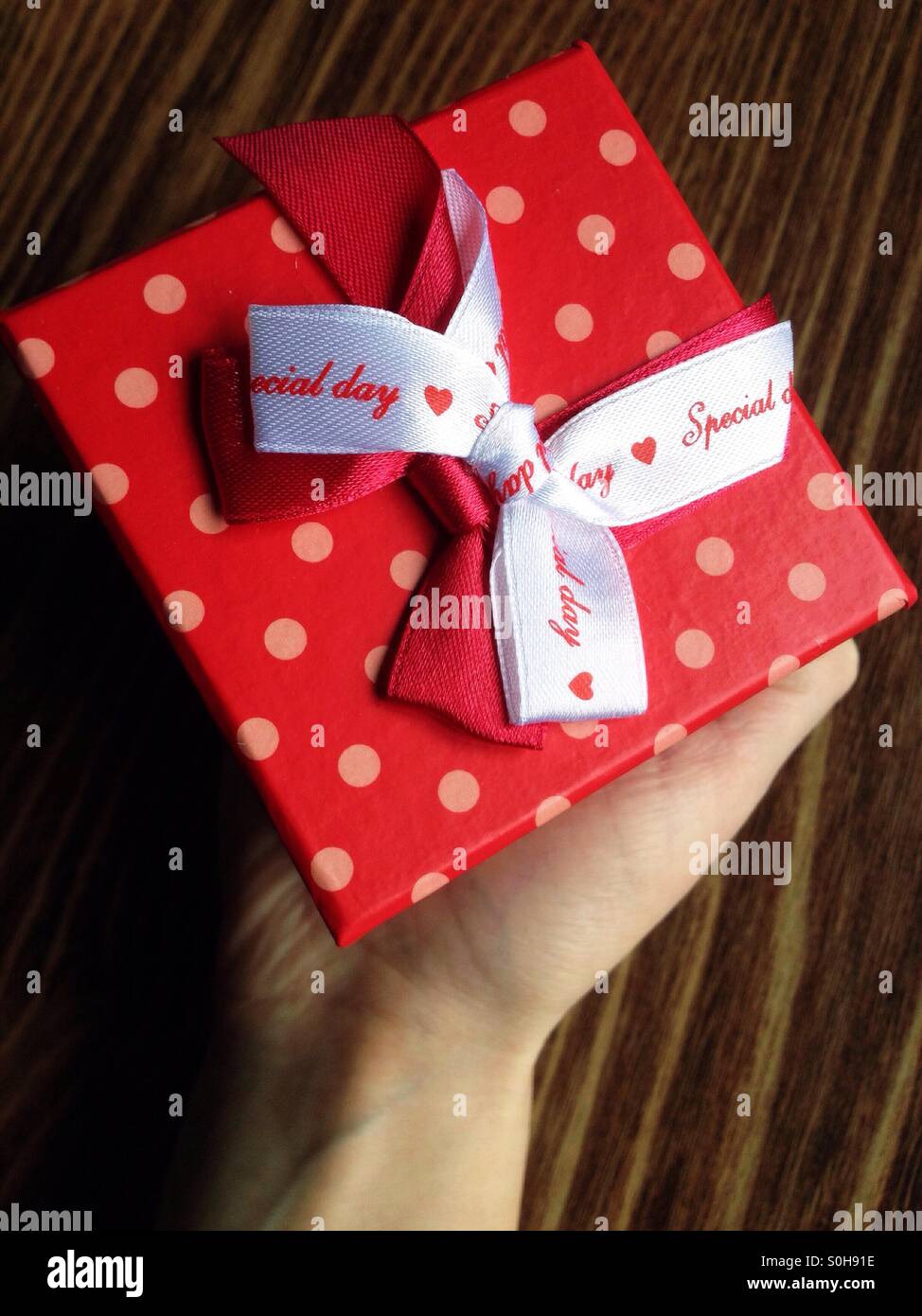 Ein Mädchen, das ein rotes Geschenk - Smartphone-aufgenommenes Stockfoto