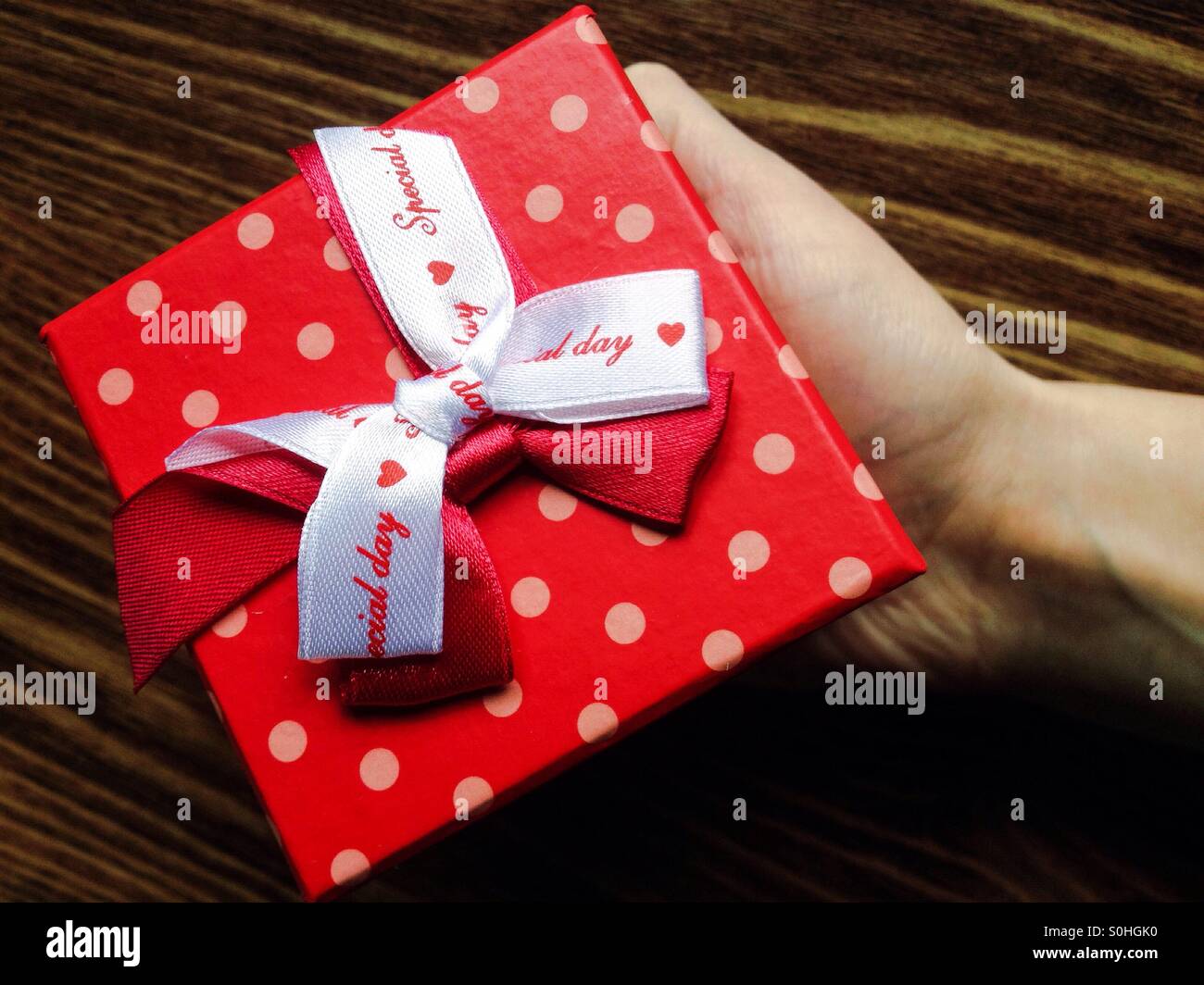 Ein Mädchen, das ein rotes Geschenk - Smartphone-aufgenommenes Stockfoto