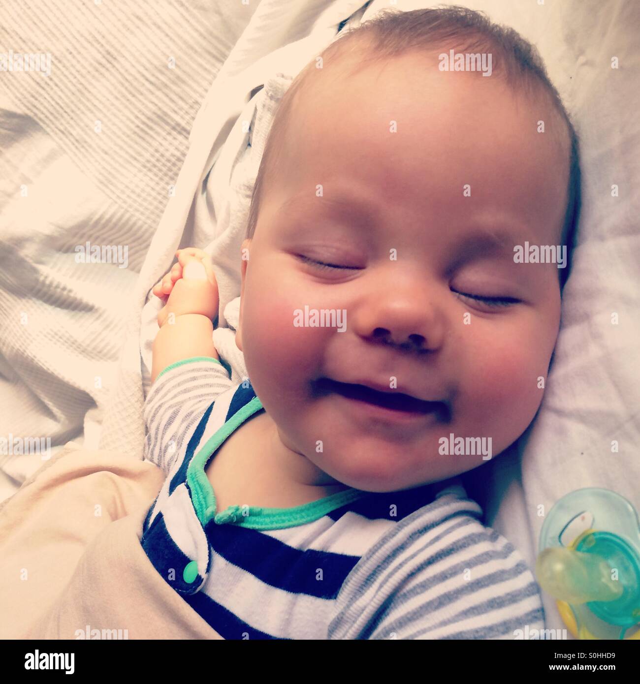 Ein 6 Monate altes Baby lächelnd in seinem Schlaf Stockfoto