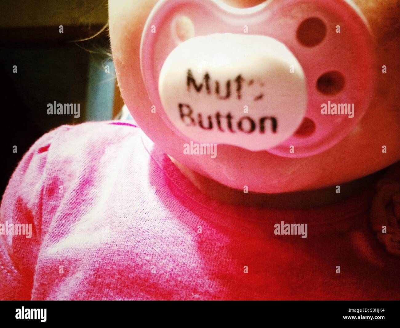 Ein kleines Mädchen Schnuller liest "mute-Taste" Stockfoto