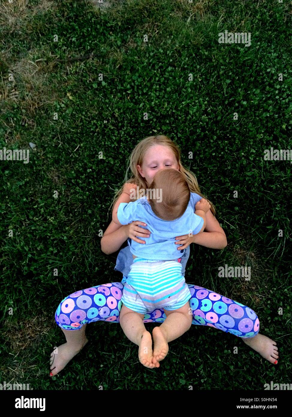 Mädchen liegend auf dem Rasen außerhalb mit ihrem Bruder Stockfoto