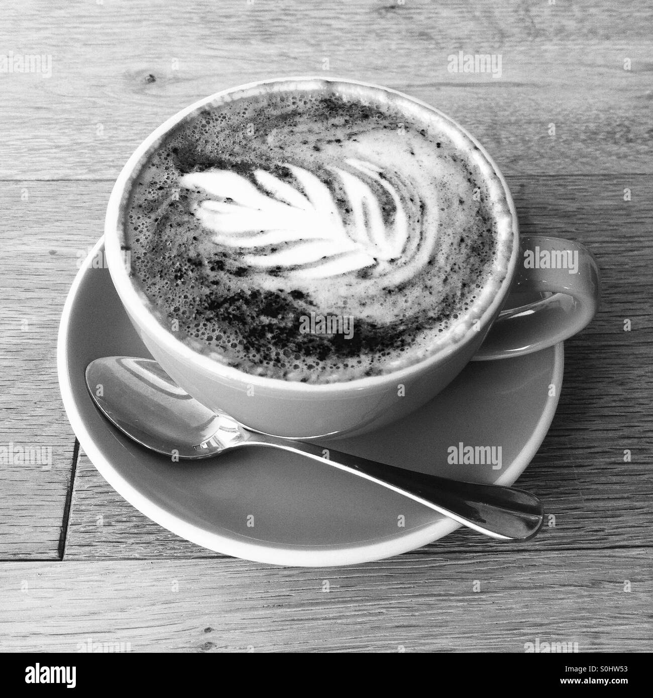 Eine Tasse Kaffee/Latte mit Bild eines Blattes im Schaum. - Smartphone-aufgenommenes Stockfoto
