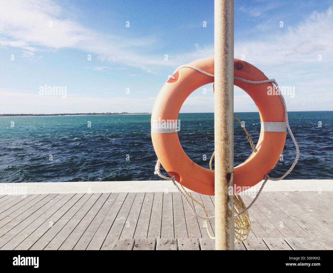 Orange lebensrettende Ring am Holzsteg, Blick auf Meer Stockfoto