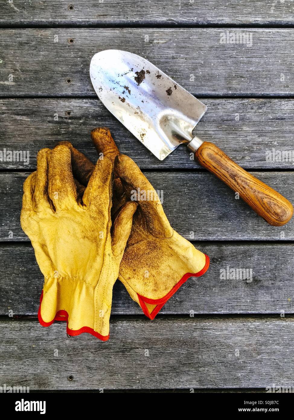 Gartenhandschuhe und Hand Kelle auf Holzterrasse Stockfoto