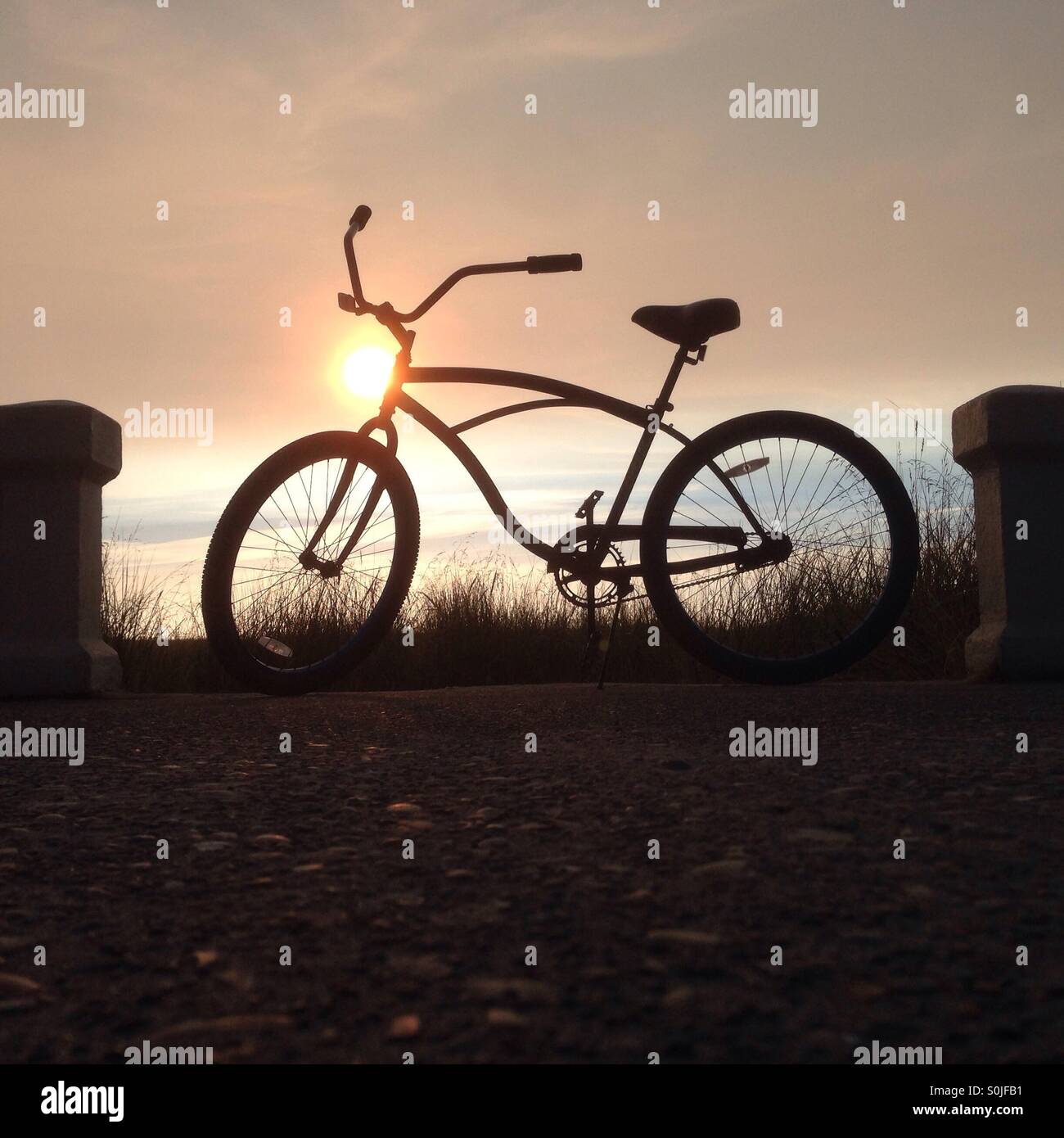 Beach Cruiser Fahrrad Silhouette bei Sonnenuntergang am Strand. Stockfoto