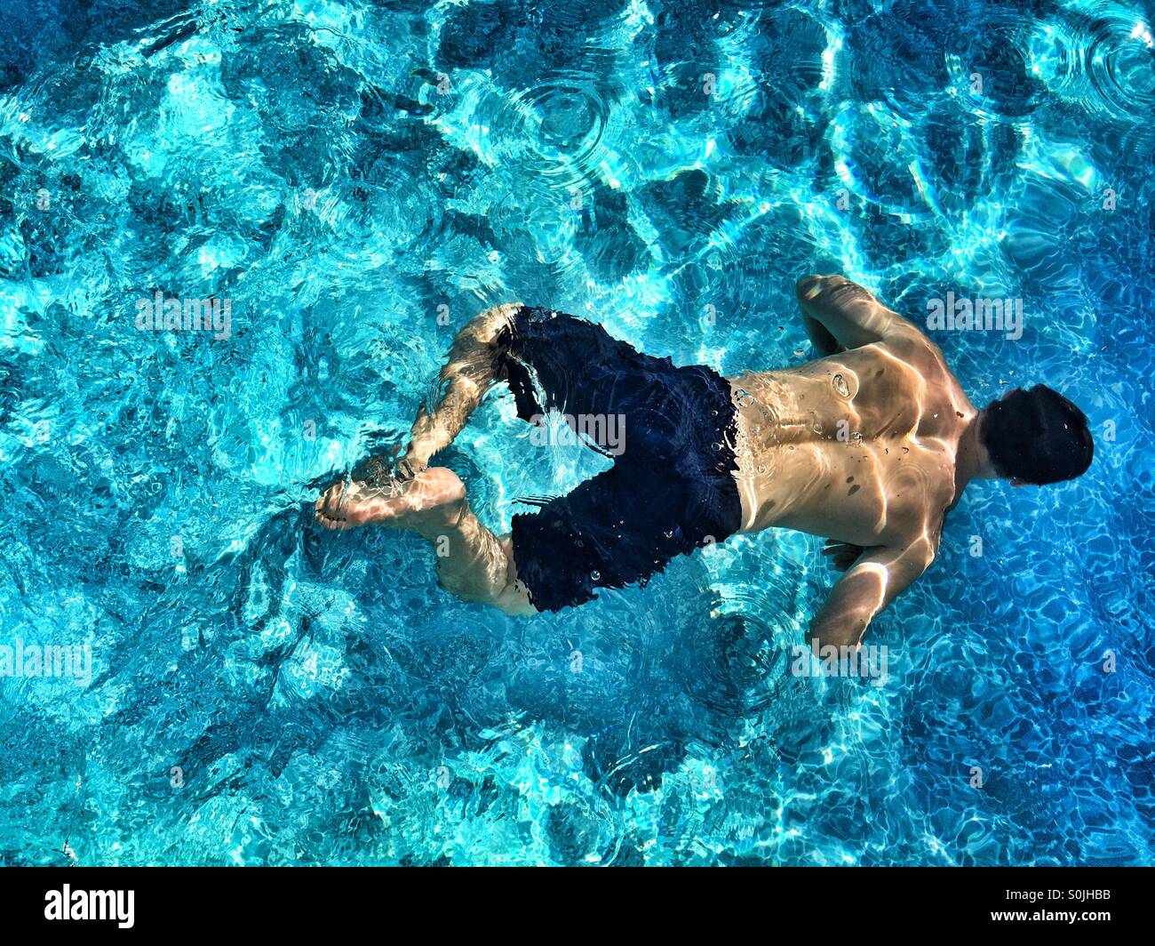 Junger Mann Schwimmen unter Wasser im Schwimmbad im Freien an einem sonnigen Tag. Foto von oben. Stockfoto