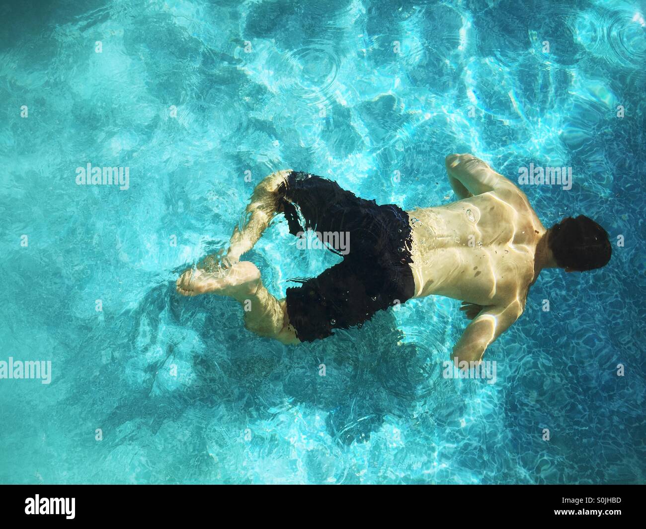 Teenager-Jungen schwimmen unter Wasser im Außenpool. Stockfoto