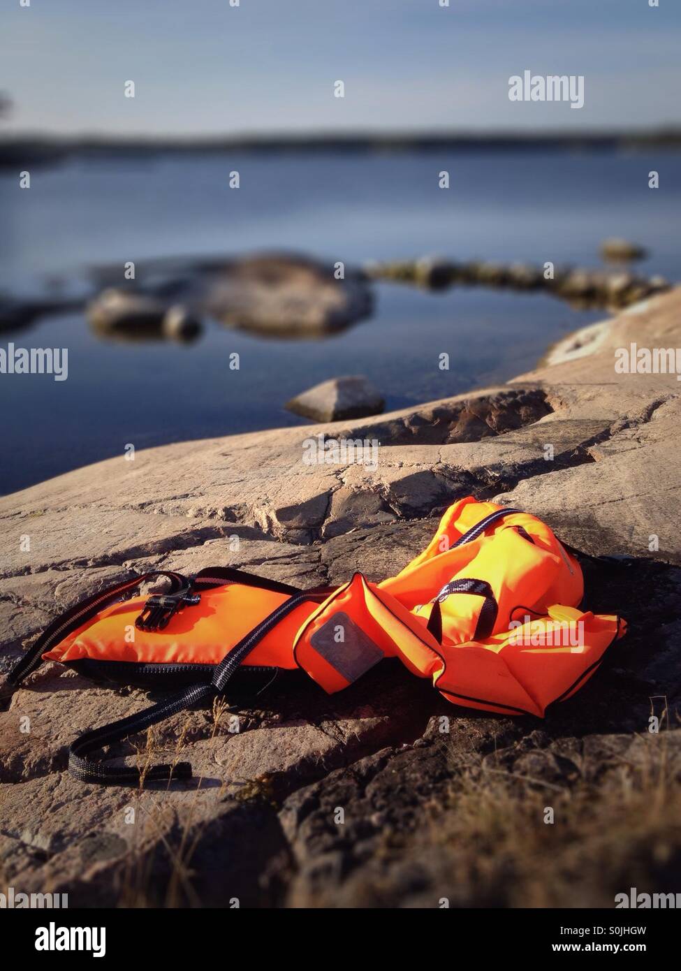 Rettungsweste Rettungsring auf Felsen in der Nähe von ruhiger Ozean liegend Stockfoto