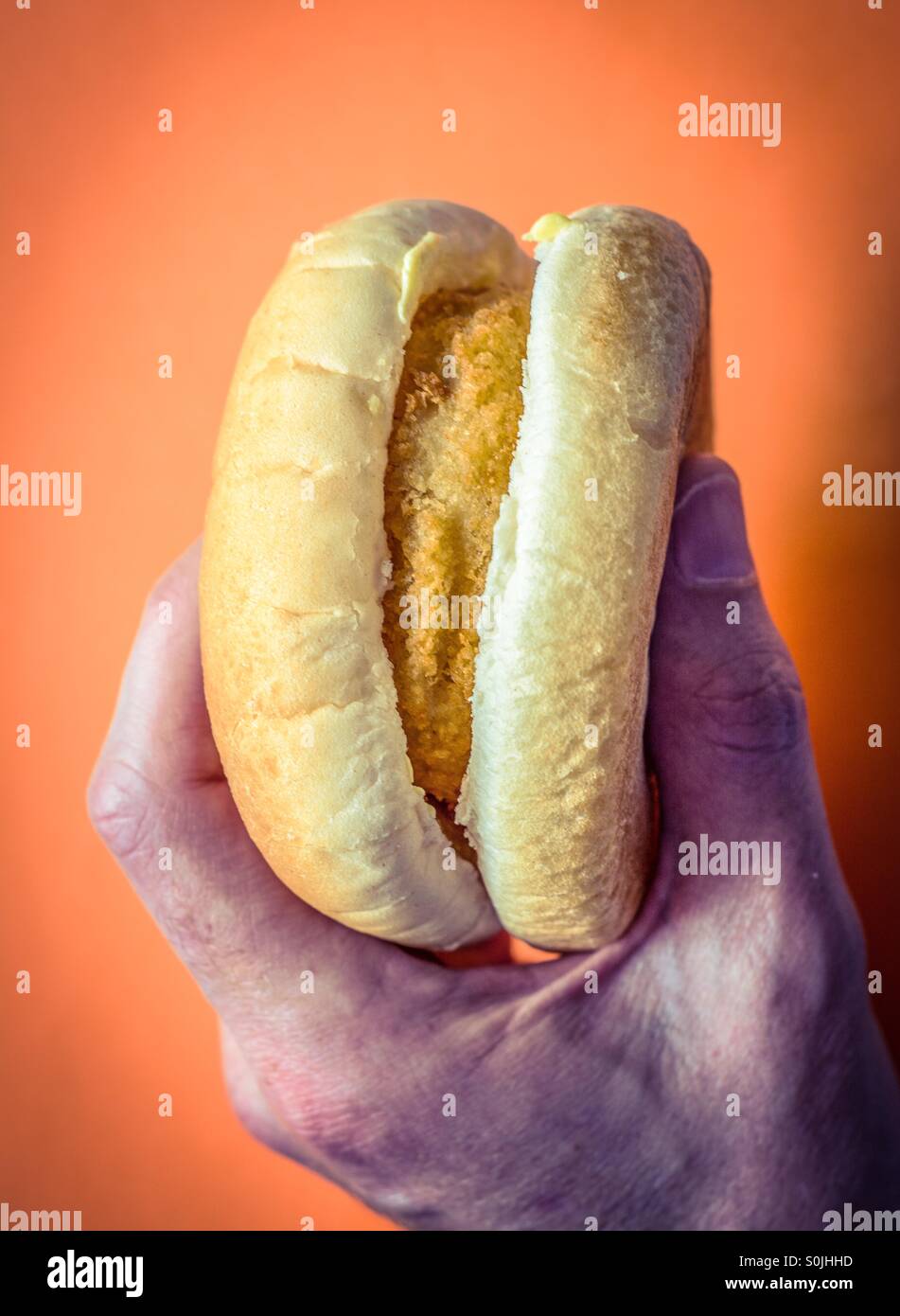 Mans Hand hält einen Fisch Kuchen-burger - Smartphone-aufgenommenes Stockfoto