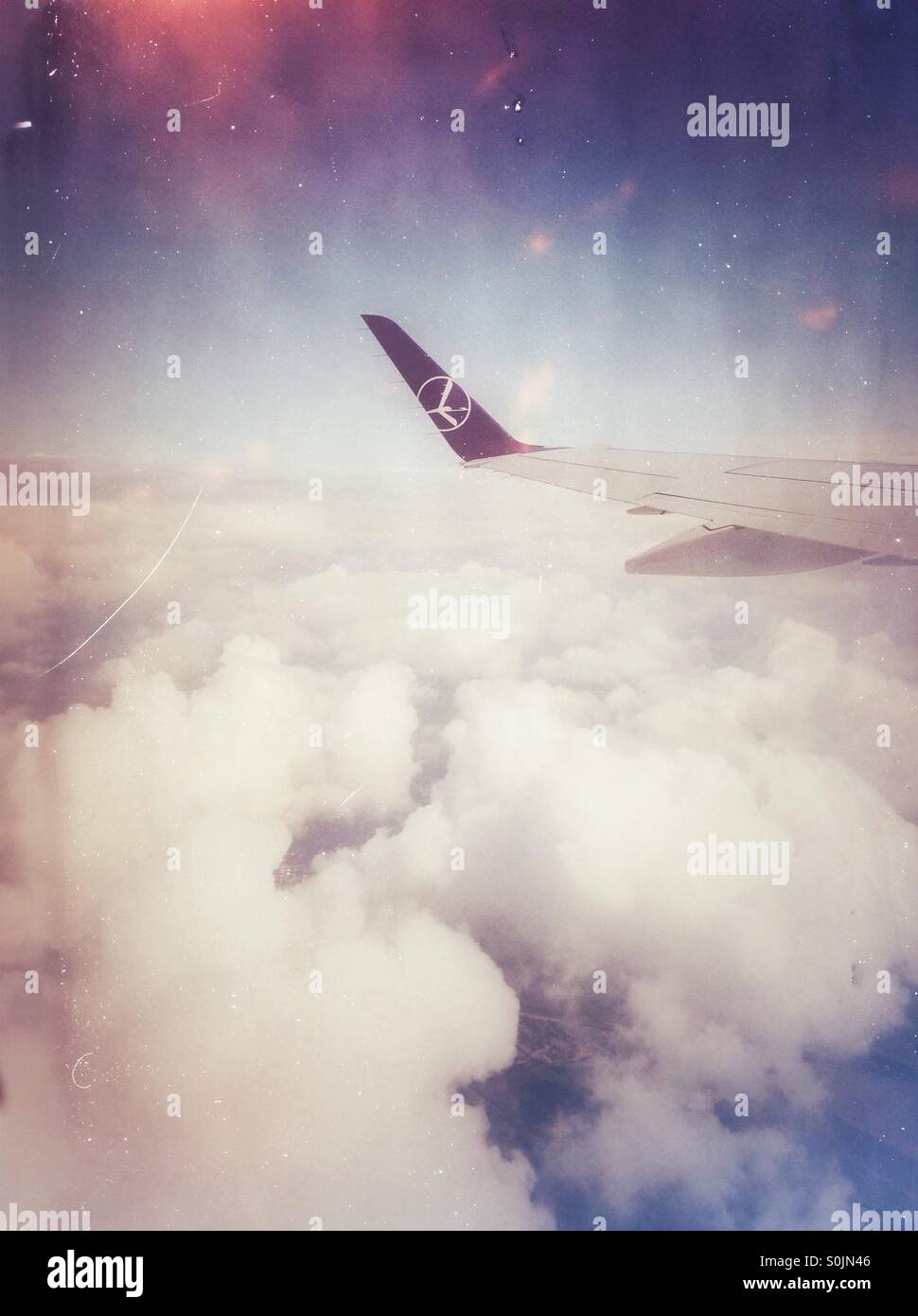 Flugreisen-Konzept mit großen Tragfläche über weiße flauschige Wolken. LOT Polish Airlines-Logo auf einem Flügel. Alten Schäden Filmeffekt. - Smartphone-aufgenommenes Stockfoto