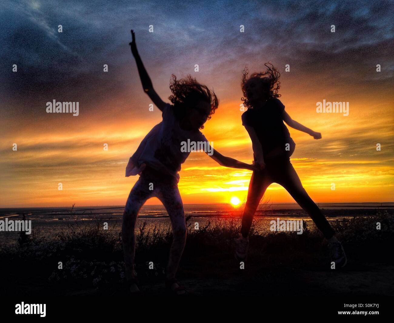 Kinder, die Spaß in der Silhouette gegen die untergehende Sonne Stockfoto