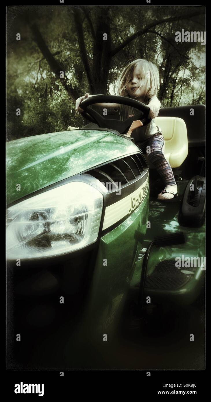 Kleinkind, die vorgibt, einen John Deere Rasenmäher fahren Stockfoto