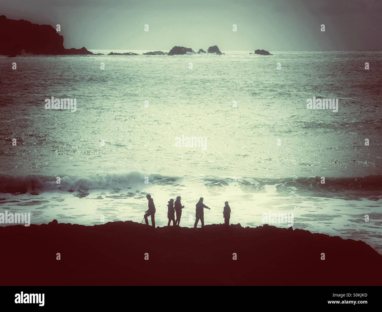 Fünf Personen gegen einen Ozean mit rollenden Wellen. Stockfoto