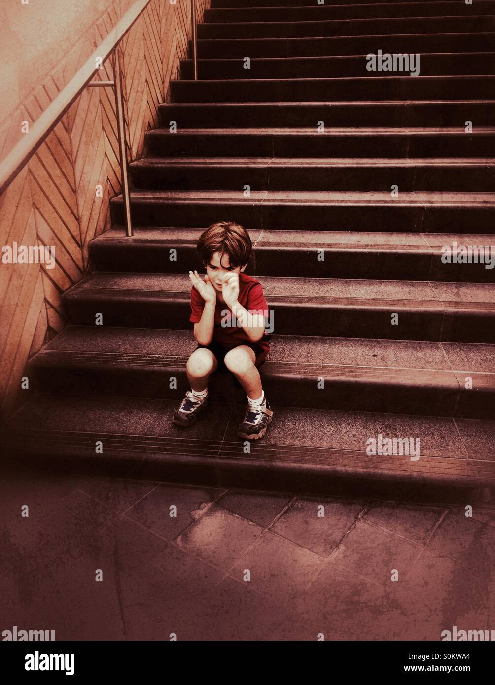 Fünf Jahren traurige Junge sitzt auf der Treppe Stockfoto