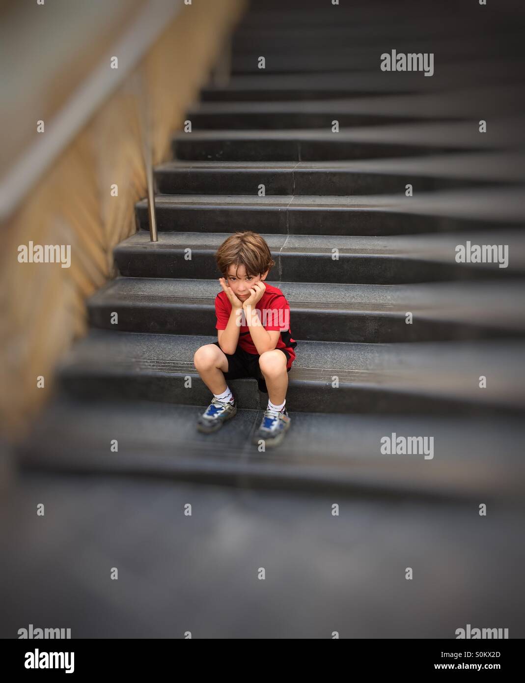 Fünf Jahre traurige junge auf Treppen mit seinen Händen auf seinem Gesicht sitzen - Smartphone-aufgenommenes Stockfoto