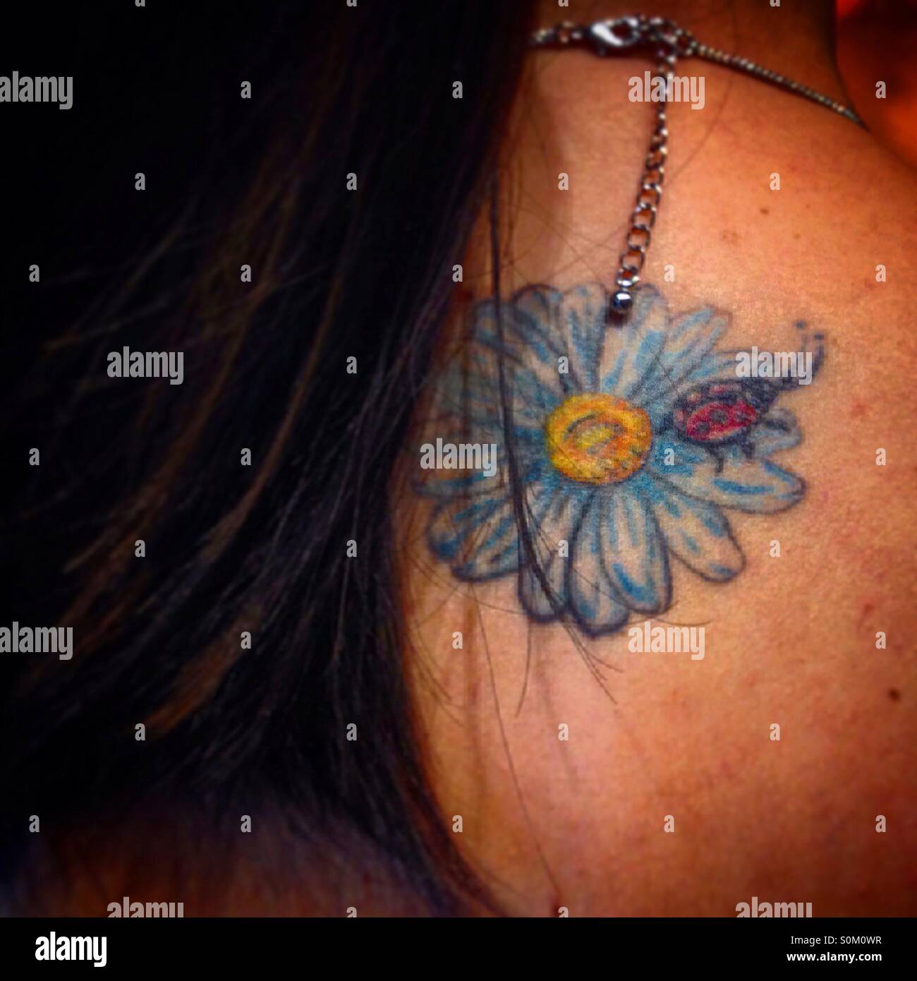 Eine Frau zeigt ein Tattoo von einem Marienkäfer auf eine blaue Blume in ihrem Rücken in Colonia Roma, Mexiko-Stadt, Mexiko - Smartphone-aufgenommenes Stockfoto