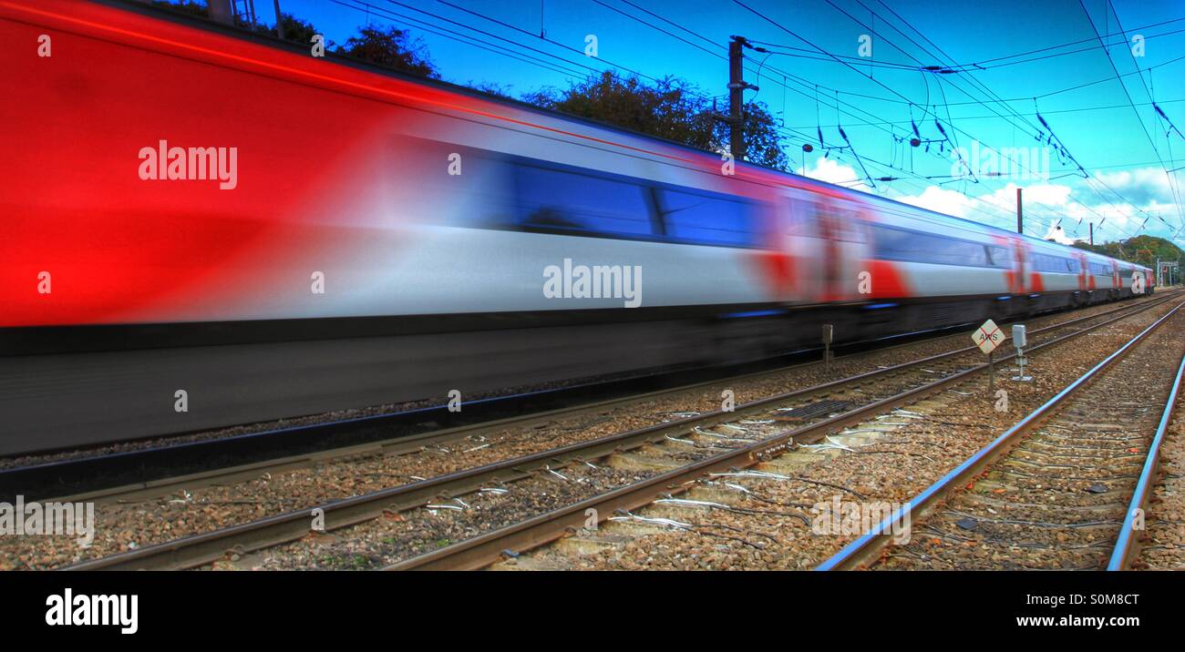 Ein rasender Zug blinkt entlang ein gerades Stück der Eisenbahnlinie. Stockfoto