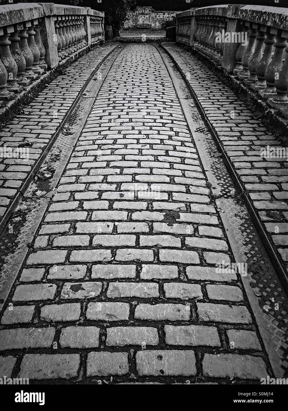 Kopfsteinpflasterstraße über historische Brücken- und Kutschenbahnen, Pollok Park, Glasgow, Schottland, Großbritannien - Smartphone-aufgenommenes Stockfoto