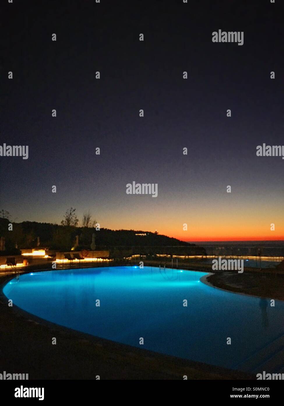 Sonnenuntergang über einem azurblauen blauen Swimmingpool Stockfoto