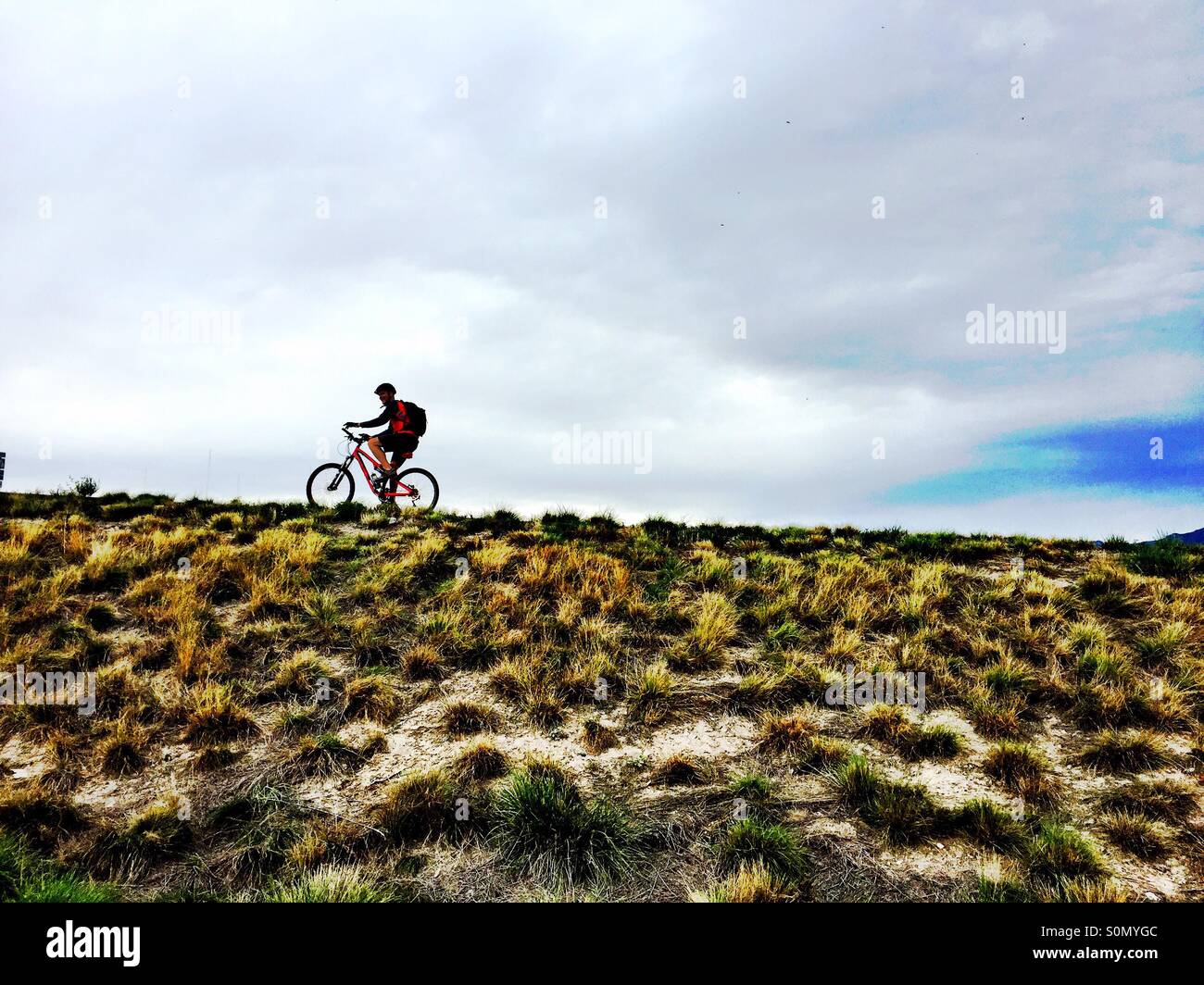 Ein Radfahrer zoomt auf dem Kamm eines Hügels im Norden Utahs auf dem Mountainbike. Stockfoto